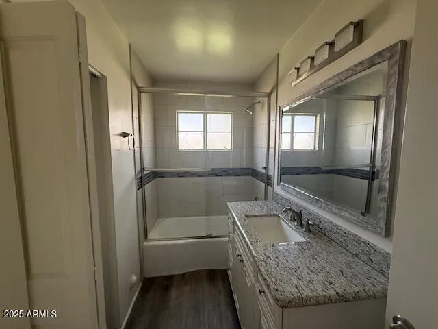 a en suite bathroom with a granite countertop tub sink and glass door