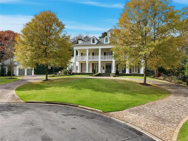 a view of a big house with a big yard and large trees