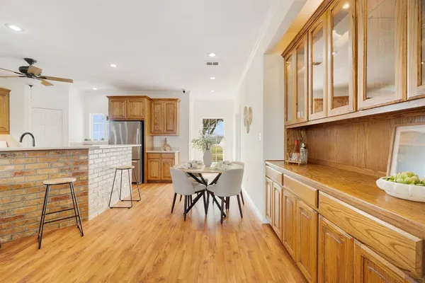 a kitchen with cabinets wooden floor and a dining table