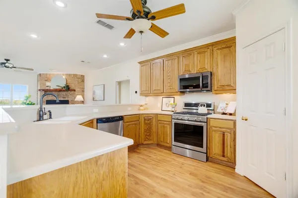 a kitchen with stainless steel appliances granite countertop a stove top oven a sink dishwasher and a refrigerator with wooden floor