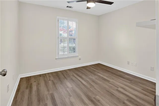 an empty room with wooden floor cabinet and windows