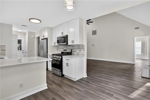 a kitchen with stainless steel appliances a sink cabinets and wooden floor
