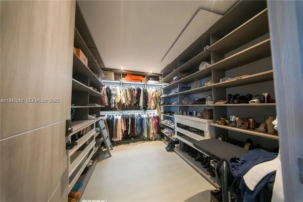 a view of walk in closet with clothes and shoes