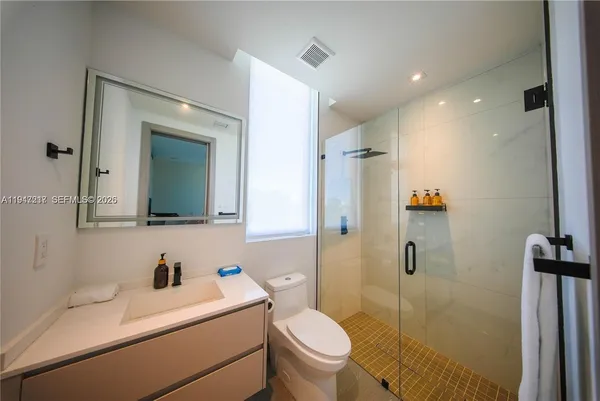 a bathroom with a sink toilet vanity and shower