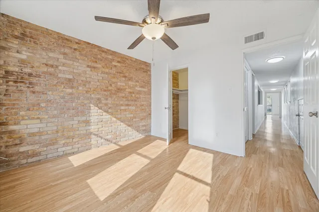 a view of a hallway with wooden floor and a ceiling fan