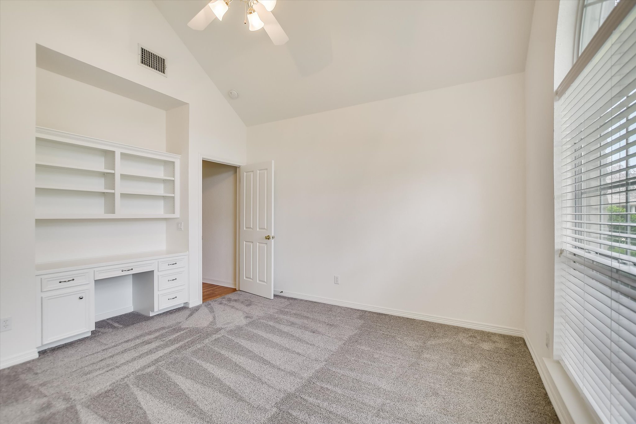 109 Stacey Cove Georgetown, TX 78628 - Photo 18 of 22 Second bedroom with arched windows, new carpet, vaulted ceiling, and built-in desk with shelves.
