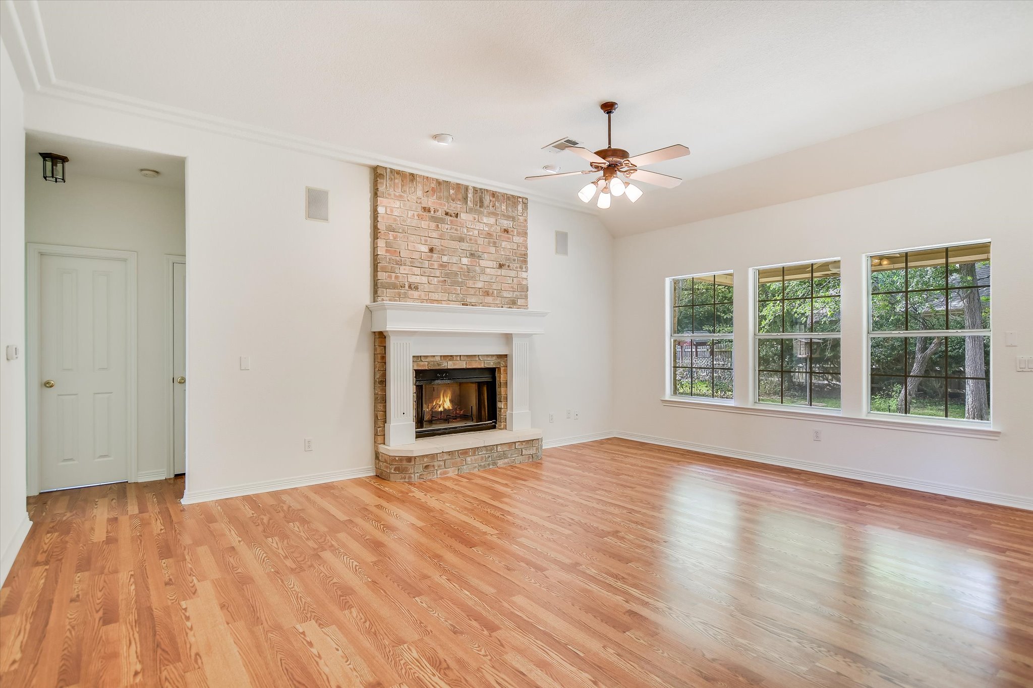 109 Stacey Cove Georgetown, TX 78628 - Photo 8 of 22 Living room area featuring a high ceiling, light wood-style flooring, a brick fireplace and views of the backyard.