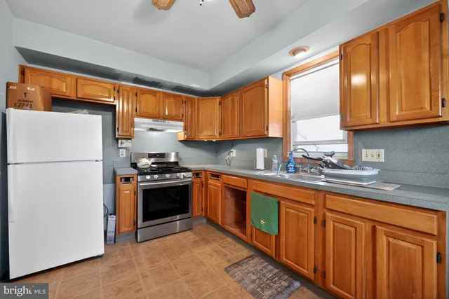 a kitchen with stainless steel appliances granite countertop a refrigerator a sink dishwasher a stove with wooden cabinets and a large window