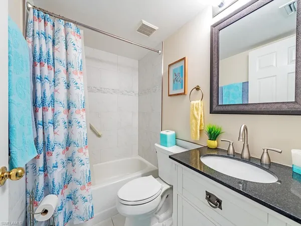 a bathroom with a granite countertop sink mirror vanity and toilet