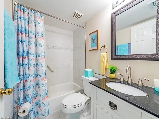 a bathroom with a granite countertop sink mirror vanity and toilet