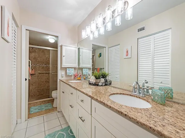 a bathroom with a granite countertop double vanity sink mirror and shower