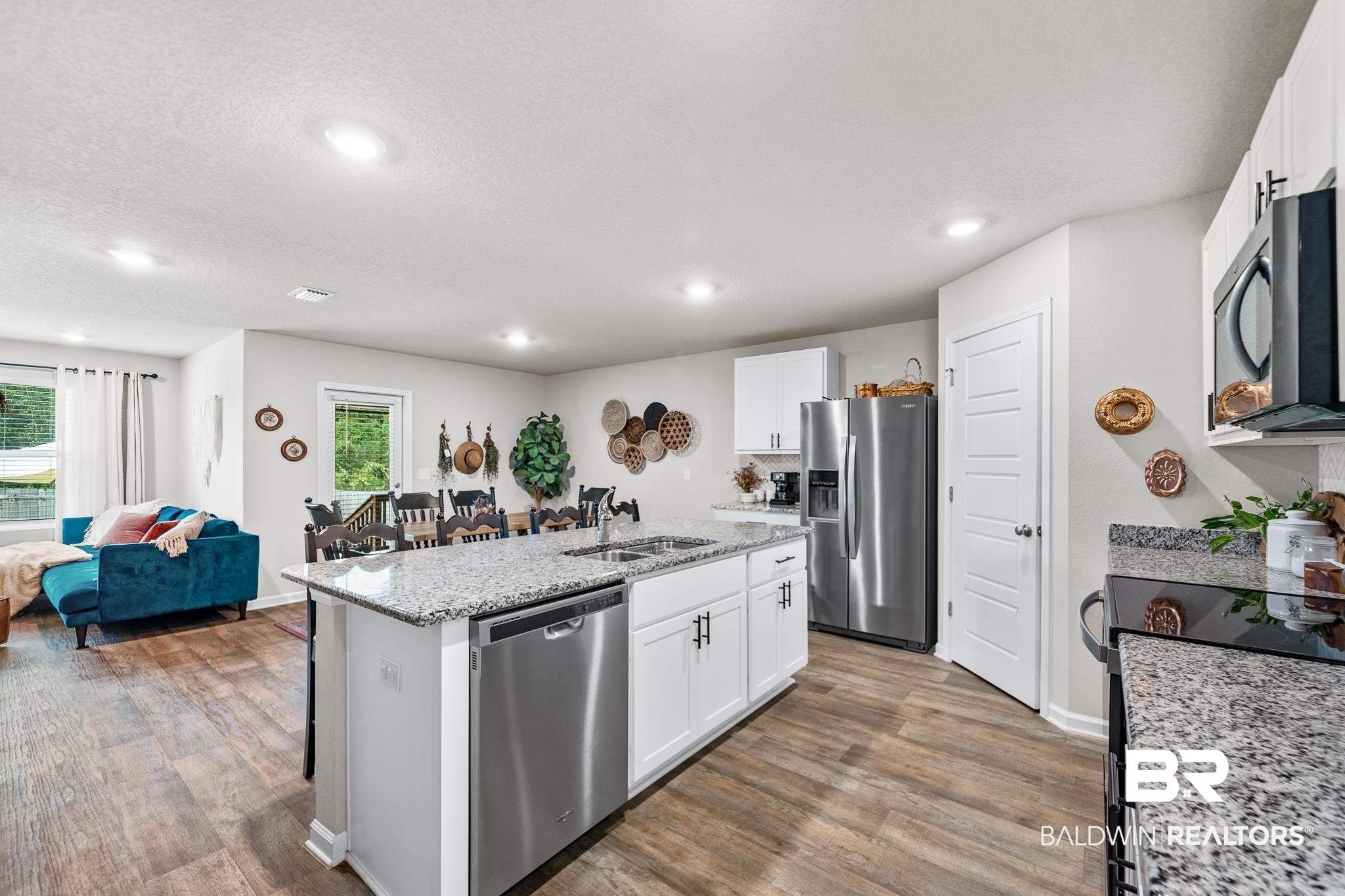 10516 Brodick Loop Daphne, AL 36527 - Photo 6 of 27 Kitchen with a center island with sink, wood-type flooring, appliances with stainless steel finishes, and white cabinets