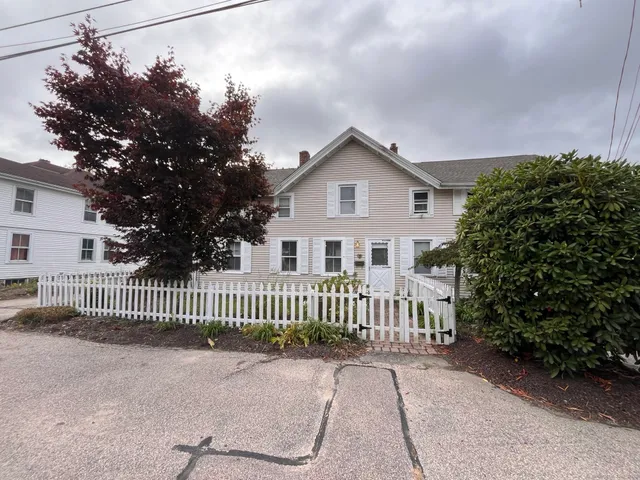 a view of a house with a small yard and wooden fence