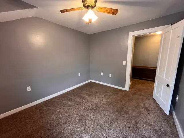 an empty room with closet and a ceiling fan