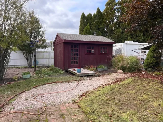 a view of a barn house next to a yard with large trees