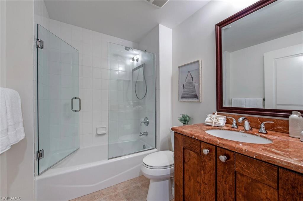 1035 Sandpiper Street, Unit F104 Naples, FL 34102 - Photo 13 of 24 a bathroom with a granite countertop toilet sink shower and mirror
