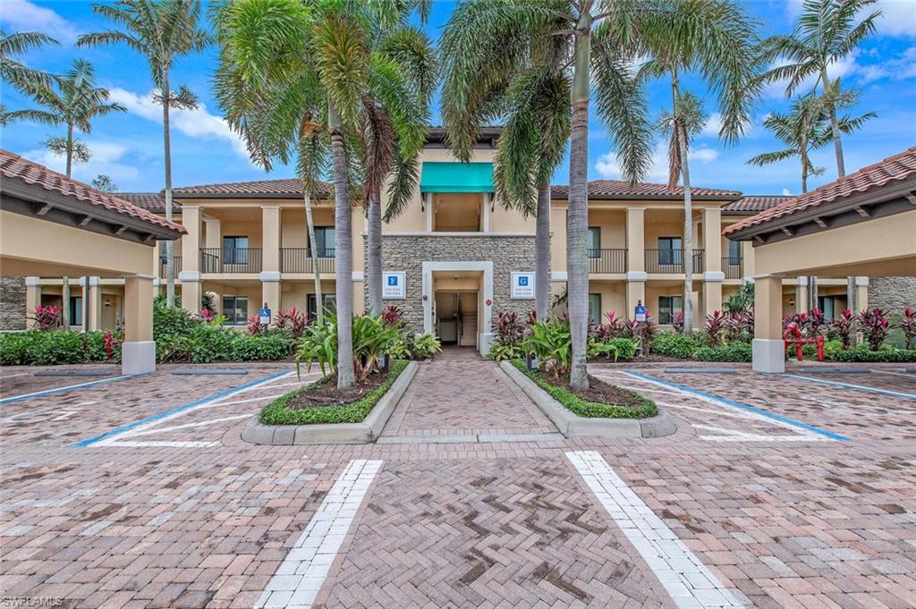 1035 Sandpiper Street, Unit F104 Naples, FL 34102 - Photo 17 of 24 front view of a brick house with a yard