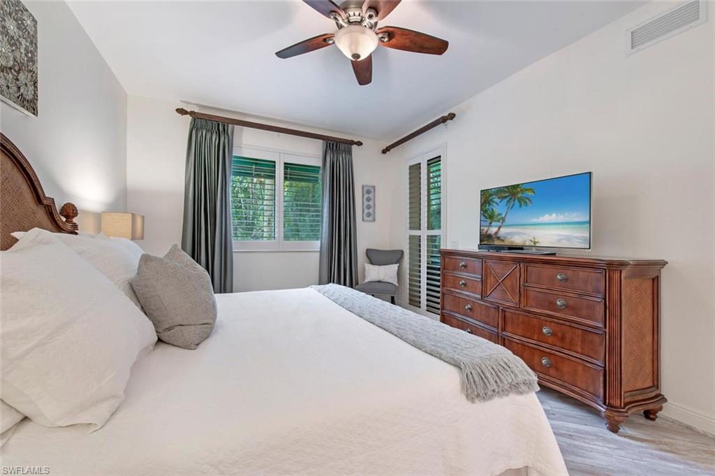 1035 Sandpiper Street, Unit F104 Naples, FL 34102 - Photo 8 of 24 a bedroom with a bed and a dresser