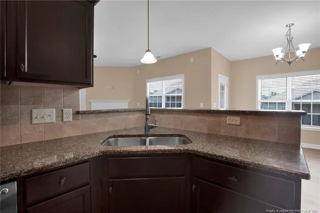 a kitchen with granite countertop stainless steel appliances a sink stove and cabinets