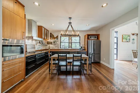 a kitchen with stainless steel appliances a dining table chairs and wooden floor