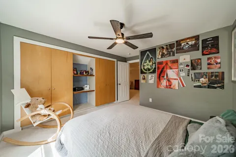 a bedroom with a bed and dresser with wooden floor