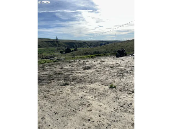 a view of a dry yard with wooden fence