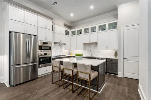 a kitchen with a refrigerator a white cabinets and wooden floor
