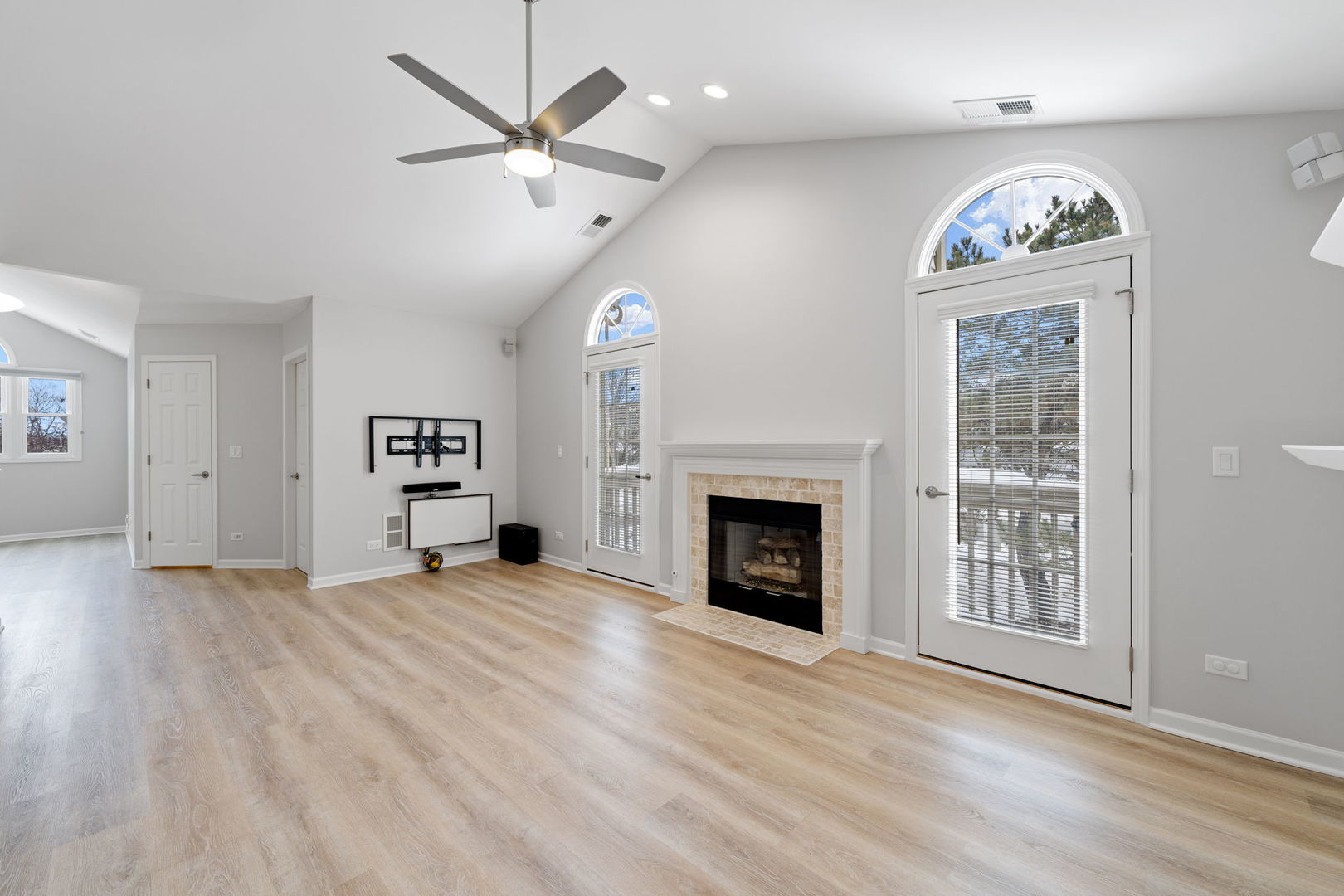 1264 Rhodes Lane Naperville, IL 60540 - Photo 30 of 35 an empty room with windows a fireplace a ceiling fan and wooden floor