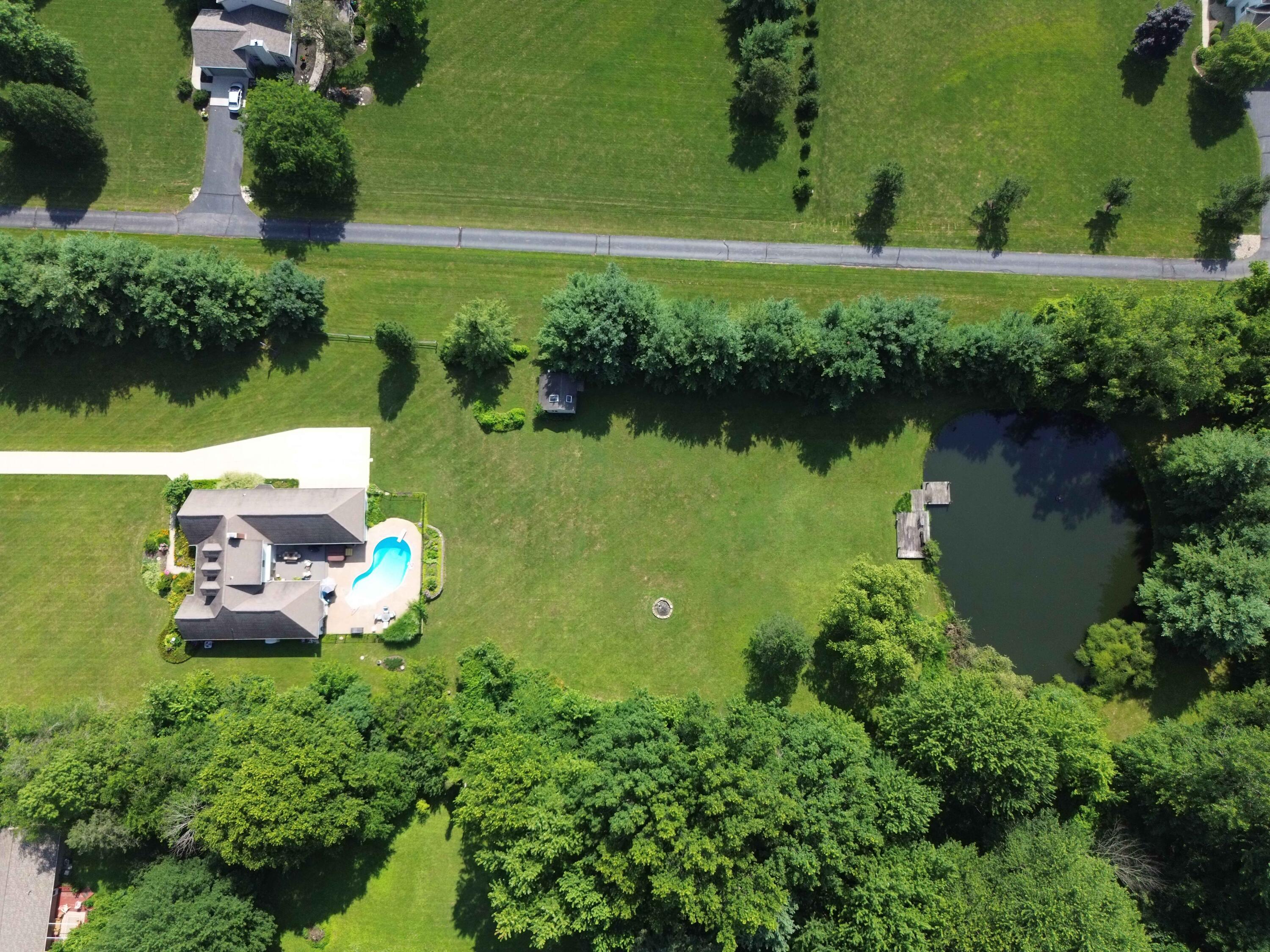 7700 Plumb Road Galena, OH 43021 - Photo 7 of 94 Aerial image captures the full depth of the property, showcasing the generous lot size, open green space, wooded perimeter, and serene pond with dock.