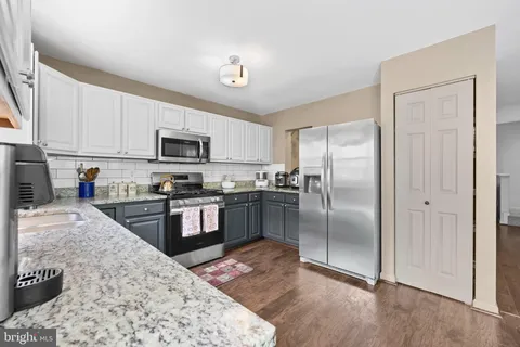 a kitchen with granite countertop a refrigerator and a stove top oven