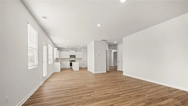 a view of a big room with wooden floor and windows