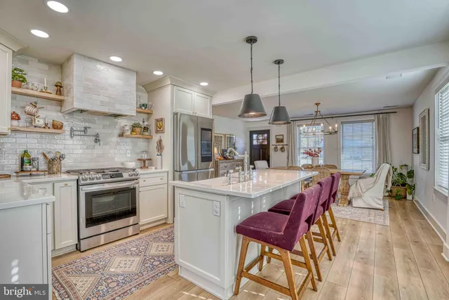 a kitchen with stainless steel appliances kitchen island granite countertop a stove a sink a refrigerator and chairs