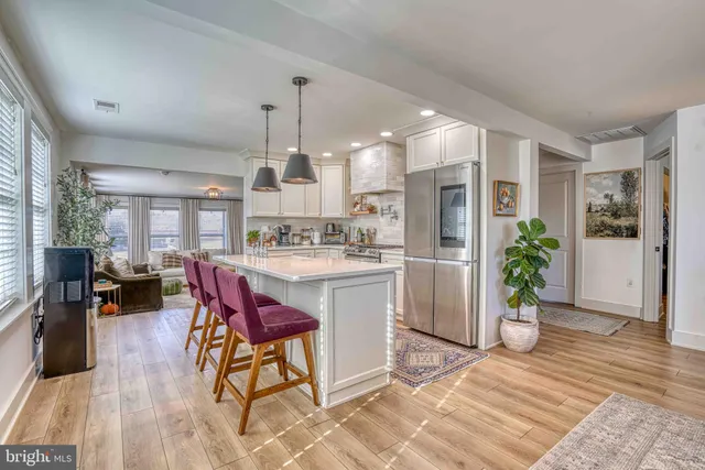 a kitchen with stainless steel appliances kitchen island granite countertop a refrigerator a stove a sink dishwasher and white cabinets with wooden floor