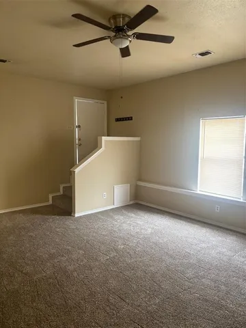 an empty room with a ceiling fan and window