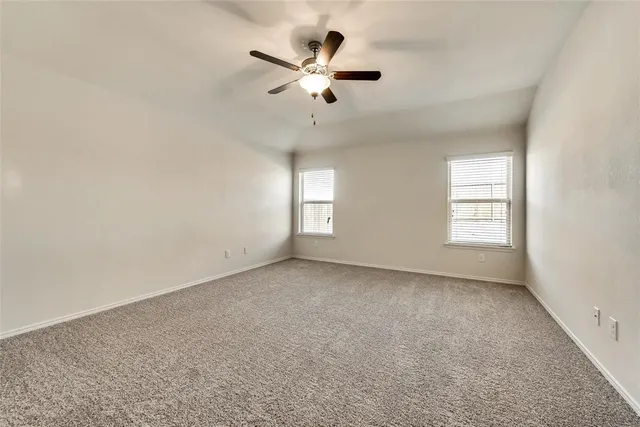 an empty room with windows and ceiling fan