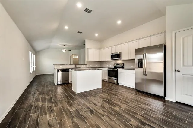 a kitchen with refrigerator a microwave and white cabinets
