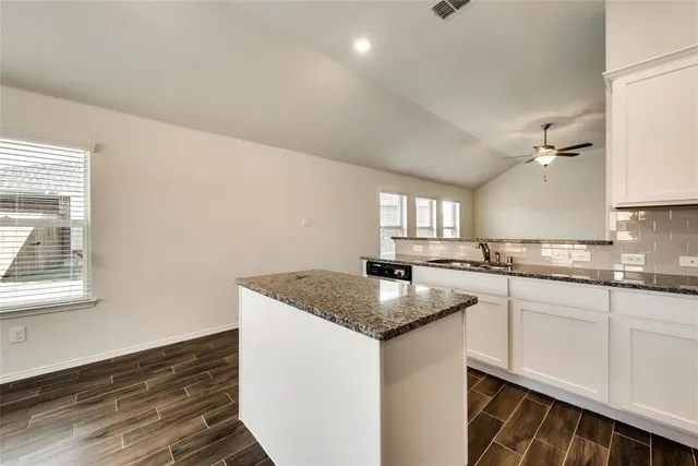 a kitchen with granite countertop white cabinets and a sink
