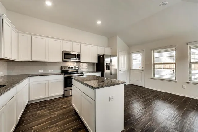 a kitchen with granite countertop a sink stove and cabinets