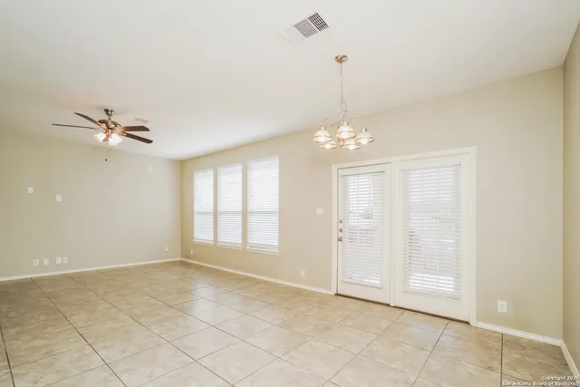 a view of an empty room with window and chandelier fan