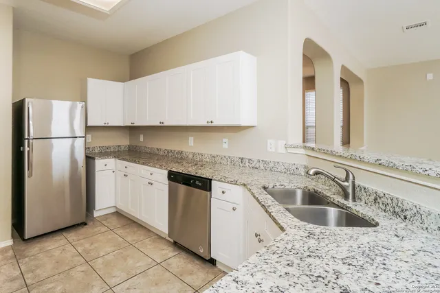 a kitchen with granite countertop a sink stove and refrigerator