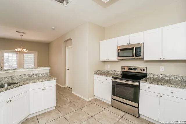 a kitchen with granite countertop white cabinets stainless steel appliances and a counter space