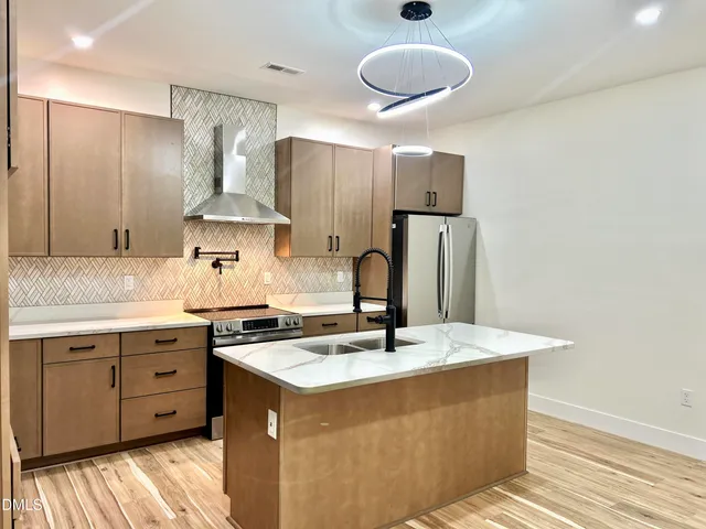 a kitchen with stainless steel appliances granite countertop a sink a stove and a refrigerator