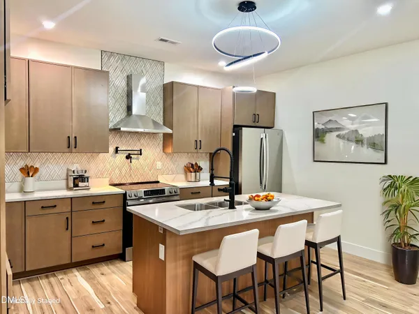 a kitchen with stainless steel appliances granite countertop a sink stove and refrigerator with wooden floor