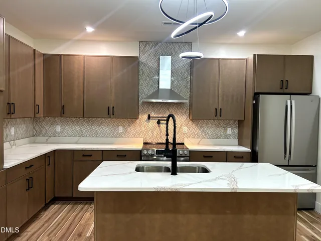 a kitchen with kitchen island granite countertop a sink a stove and refrigerator