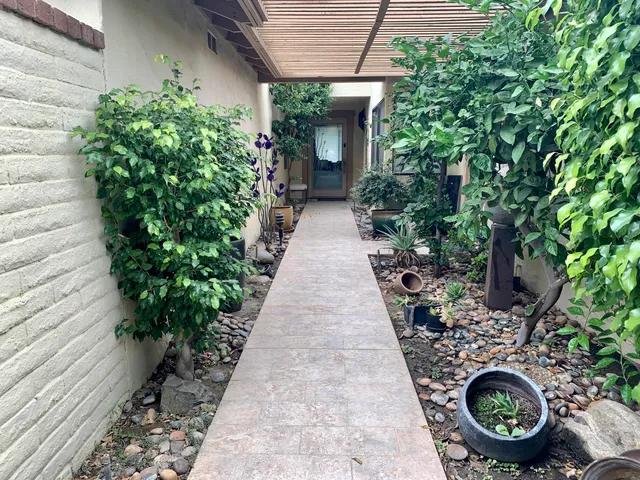 a view of a pathway of house with potted plants