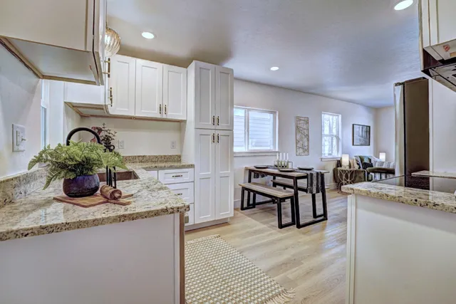 an empty room with wooden floor a chandelier fan and windows