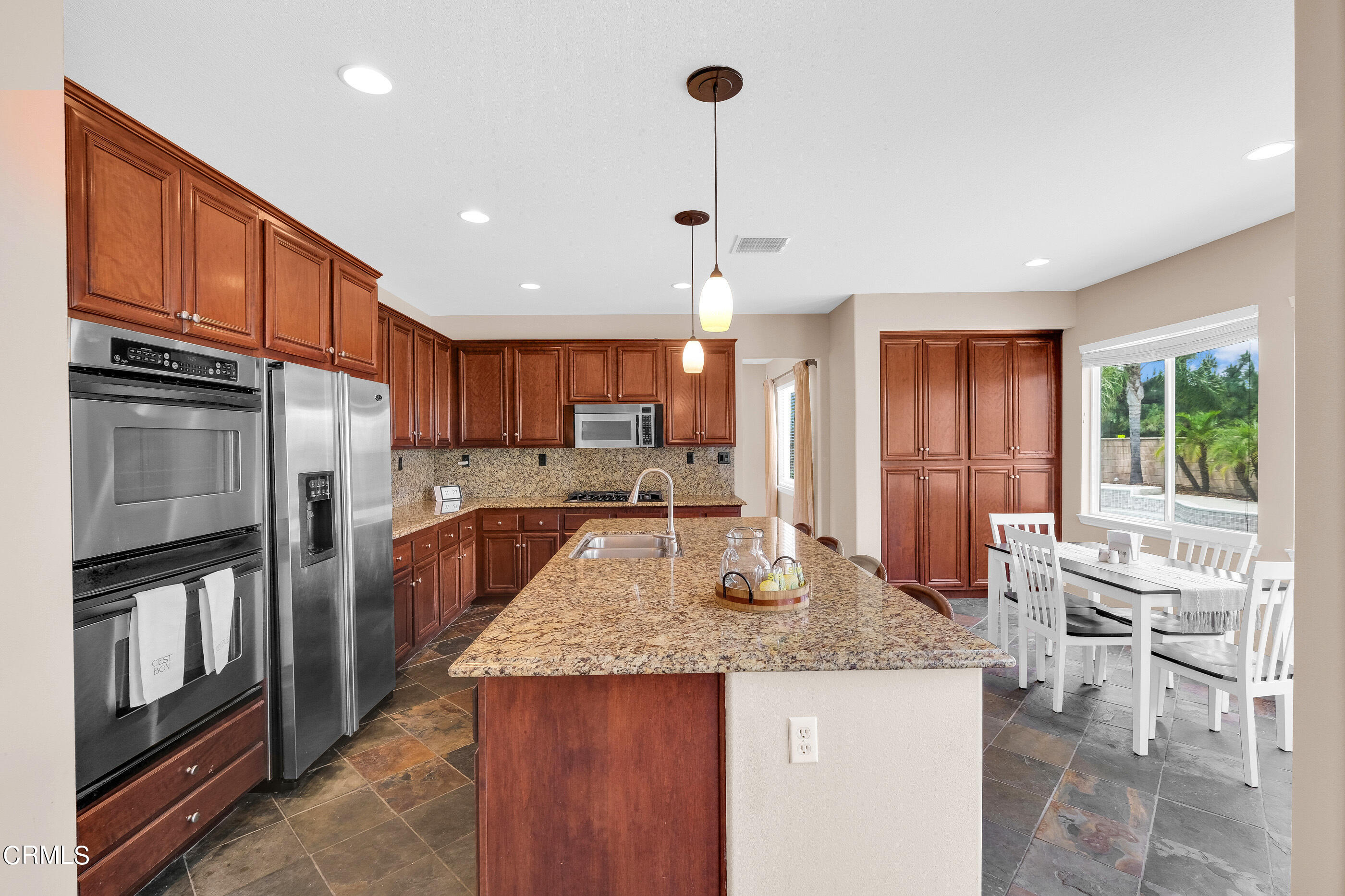 8317 Carriage Court Riverside, CA 92508 - Photo 16 of 37 a kitchen with granite countertop kitchen island stainless steel appliances a refrigerator a stove a sink a dining table and chairs