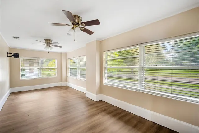 a view of an empty room with wooden floor and a window