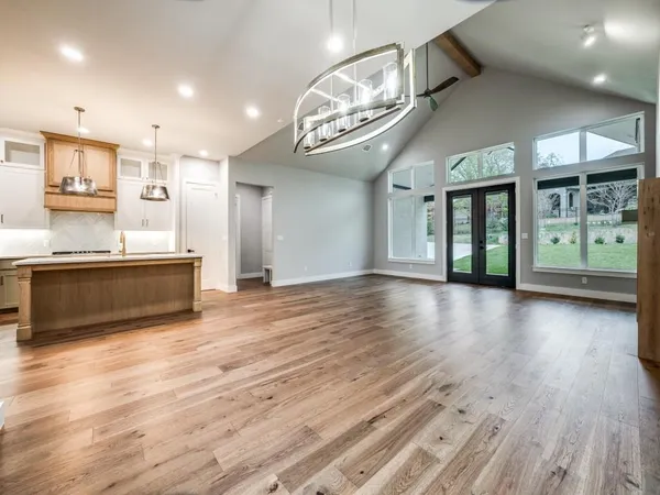 an empty room with wooden floor fireplace and windows