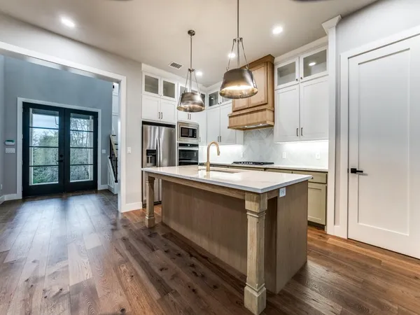 a kitchen with stainless steel appliances granite countertop a refrigerator a stove and a wooden floors
